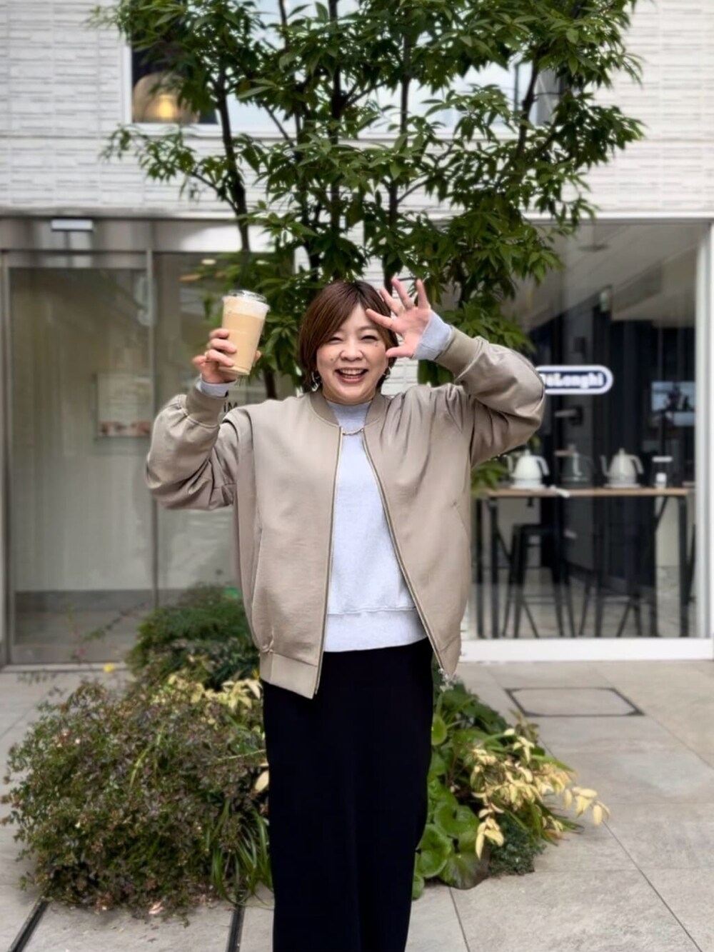 グリーン系のブルゾン、グレー系のニット/セーター、ブラック系のスカートを着用したレディースの春コーディネートの3枚目の写真