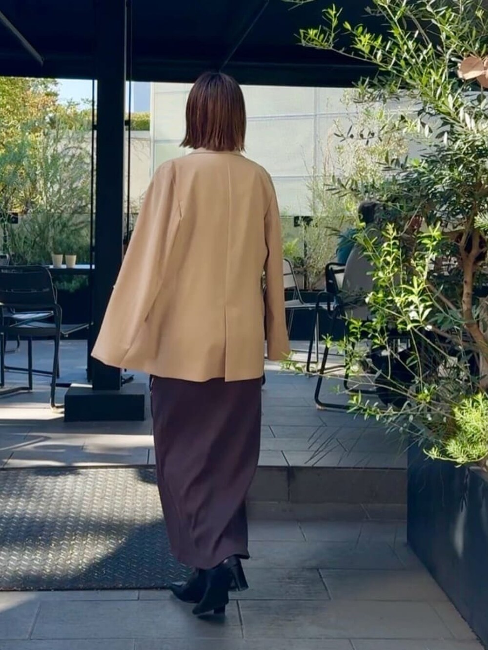 イエロー系のテーラードジャケット、ブラウン系のワンピース、ブラック系のバッグを着用したレディースの秋コーディネートの3枚目の写真