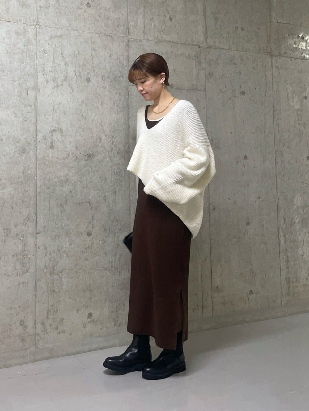 ホワイト系のニット/セーター、ブラウン系のワンピース/ドレス、ブラック系のハンドバッグを着用したレディースの冬コーディネートの3枚目の写真