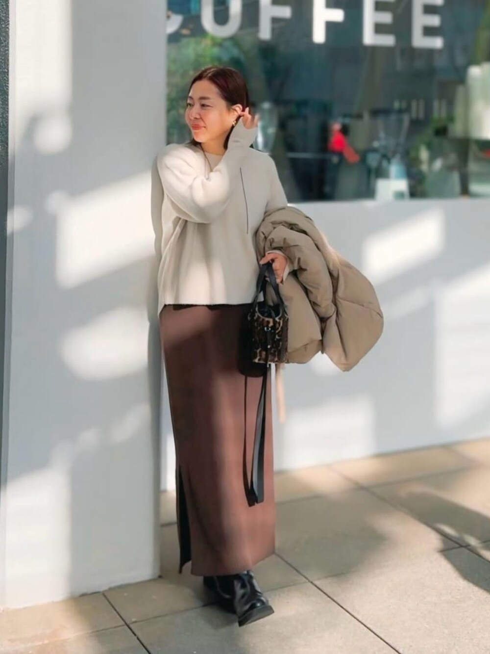 ホワイト系のニット/セーター、ブラウン系のワンピースを着用したレディースの冬コーディネートの2枚目の写真