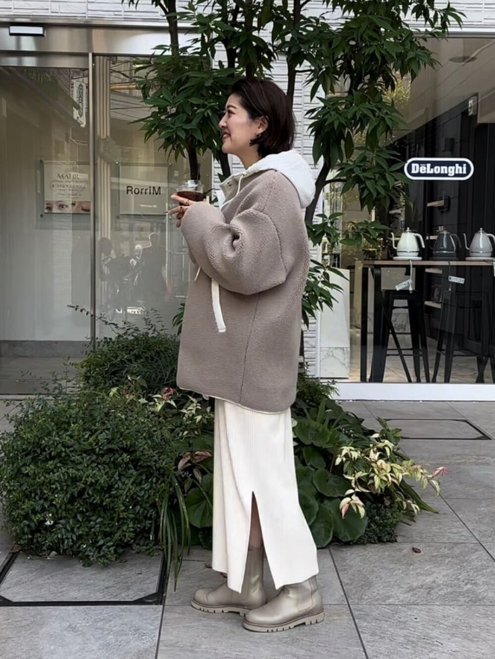 ベージュ系のその他アウター、ホワイト系のワンピース、ベージュ系のブーツを着用したレディースの冬コーディネートの2枚目の写真