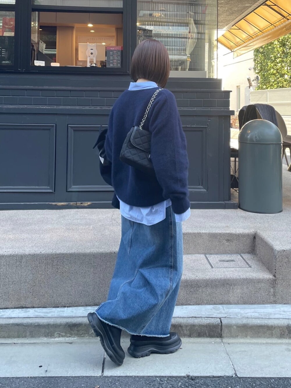 ブルー系のニット/セーター、ブルー系のデニムスカート、ブラック系のブーツを着用したレディースの冬コーディネートの3枚目の写真