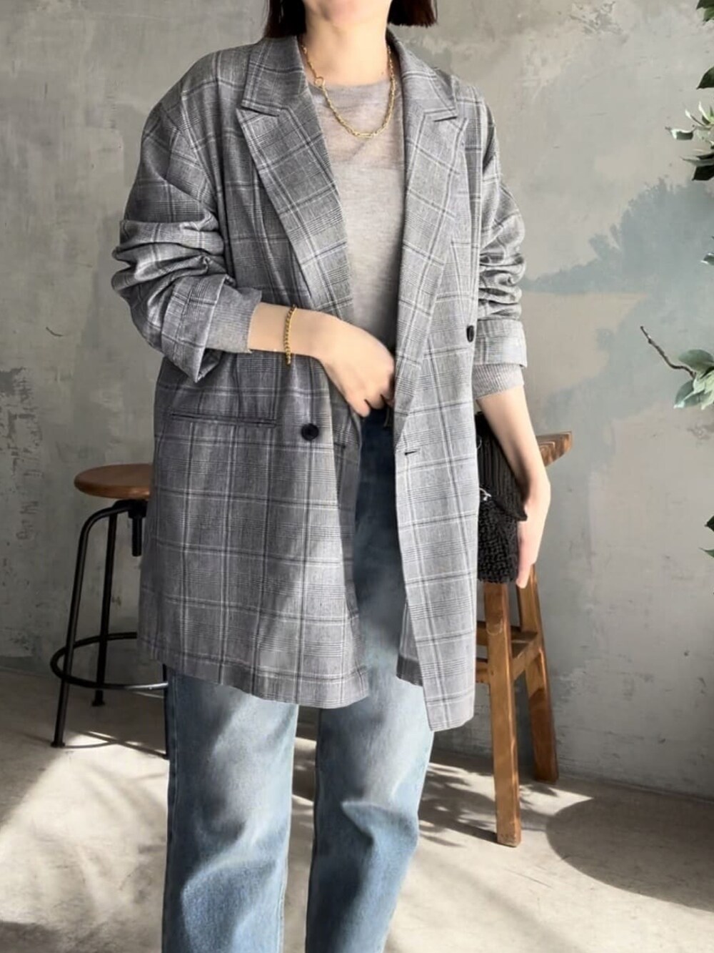 グレー系のテーラードジャケット、ブラック系のショルダーバッグ、ブルー系のデニムパンツを着用したレディースの春コーディネートの4枚目の写真