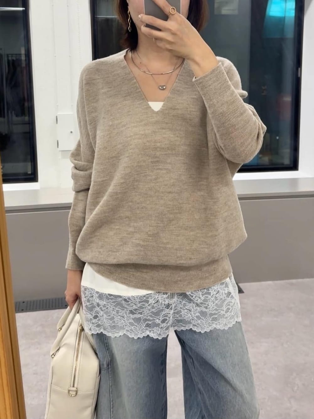 ベージュ系のニット/セーター、ホワイト系のキャミソール、ホワイト系のボストンバッグを着用したレディースの冬コーディネートの4枚目の写真