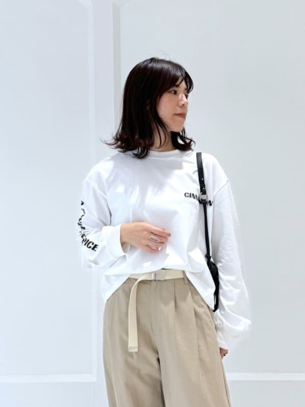 ベージュ系のチノパンツ、ホワイト系のTシャツ/カットソー、ブラック系のボディバッグ/ウエストポーチを着用したレディースの冬コーディネートの2枚目の写真