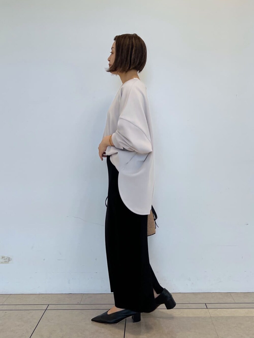 グレー系のTシャツ/カットソー、ブラック系のスカート、ブラック系のハンドバッグを着用したレディースの春コーディネートの2枚目の写真
