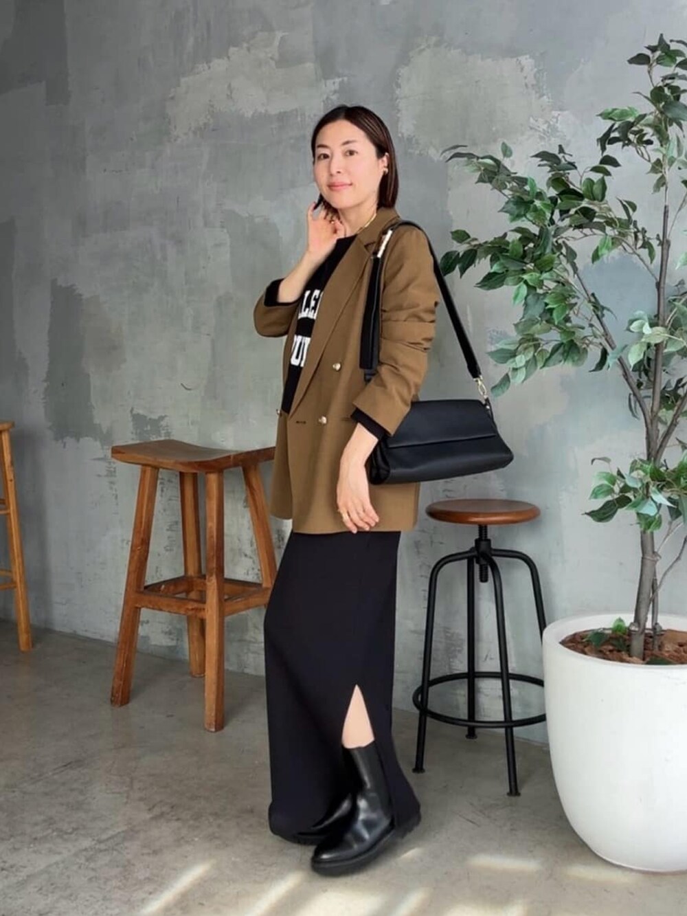 ブラック系のスウェット、ブラウン系のテーラードジャケット、ブラック系のワンピースを着用したレディースの秋コーディネートの2枚目の写真