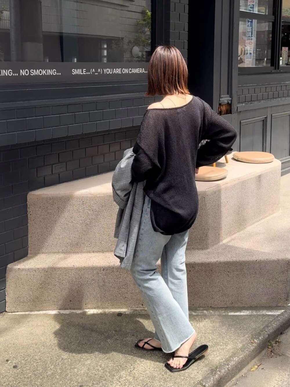 ブラック系のニット/セーター、ブルー系のデニムパンツ、ブラック系のサンダルを着用したレディースの春コーディネートの2枚目の写真