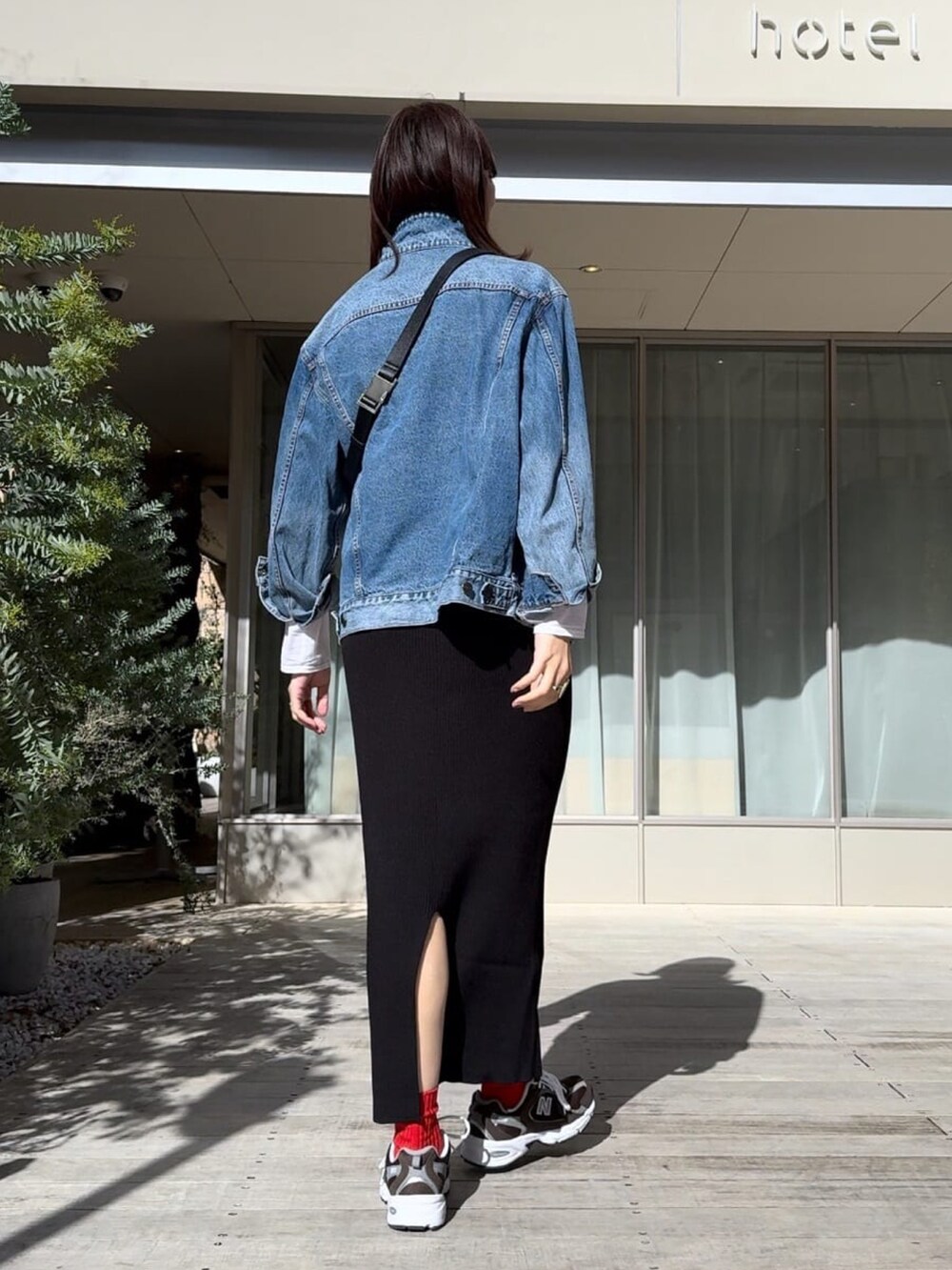 ブラック系のボディバッグ/ウエストポーチ、ブルー系のデニムジャケット、ブラック系のスカートを着用したレディースの冬コーディネートの4枚目の写真