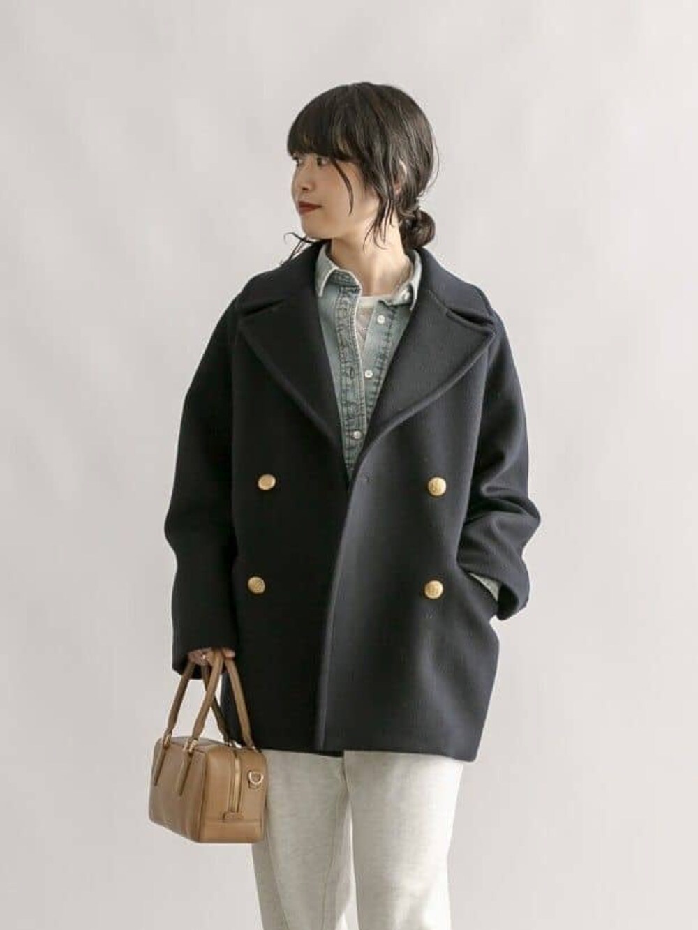 グレー系のスウェットパンツ、イエロー系のボストンバッグ、ブルー系のピーコートを着用したレディースの冬コーディネートの4枚目の写真