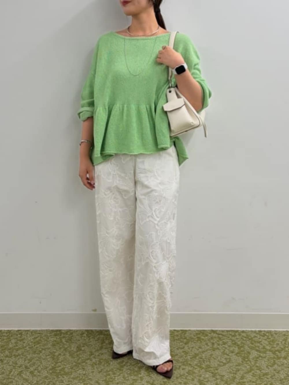 ホワイト系のショルダーバッグ、ブラウン系のサンダル、グリーン系のニット/セーターを着用したレディースの春コーディネートの3枚目の写真