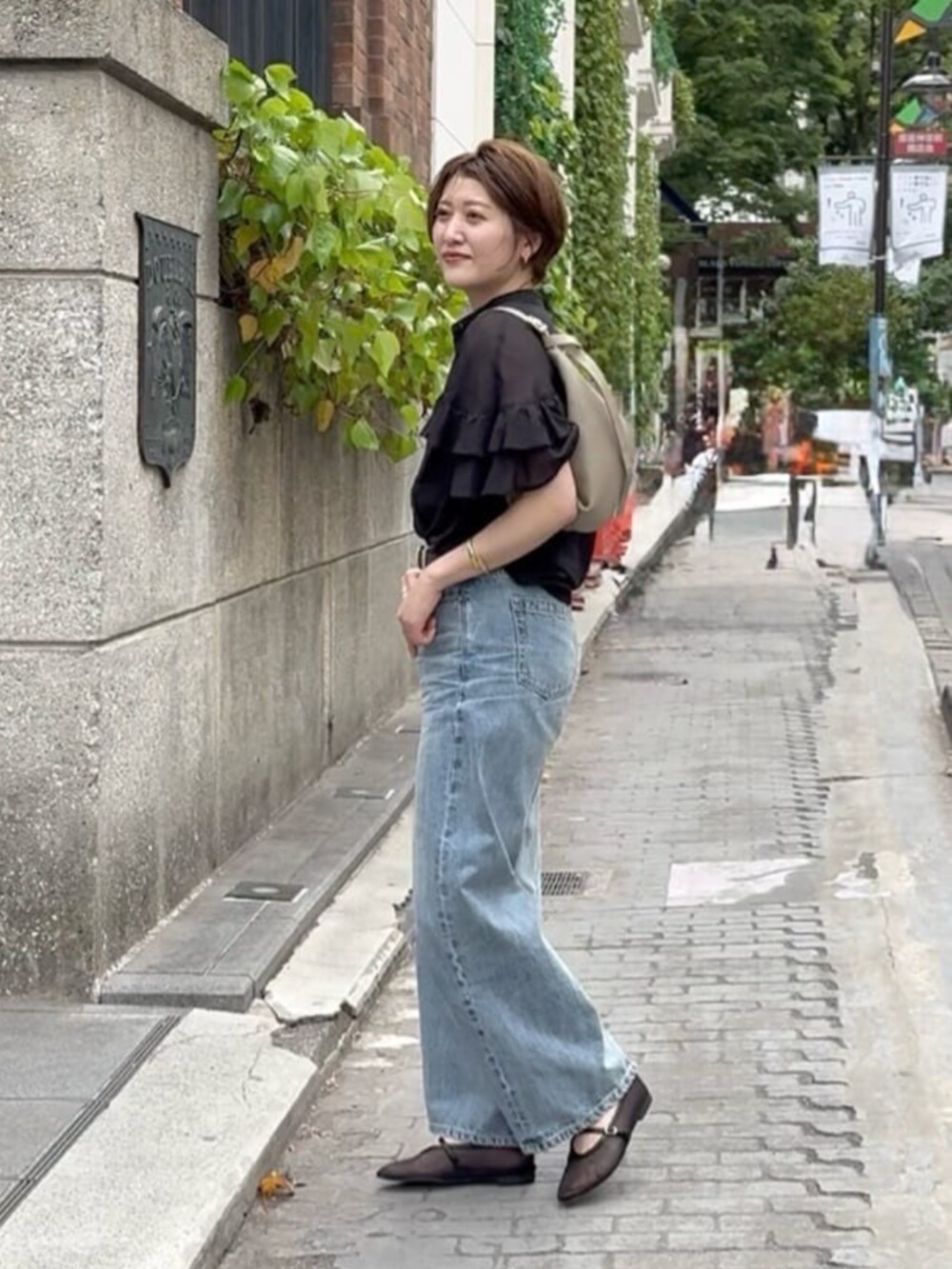 ブラック系のその他シューズ、ブルー系のデニムパンツ、ベージュ系のショルダーバッグを着用したレディースの春コーディネートの3枚目の写真