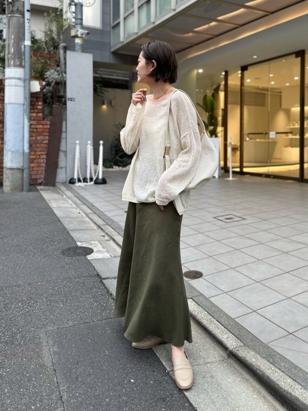 ホワイト系のニット/セーター、ホワイト系のキャミソール、グリーン系のスカートを着用したレディースの春コーディネートの2枚目の写真