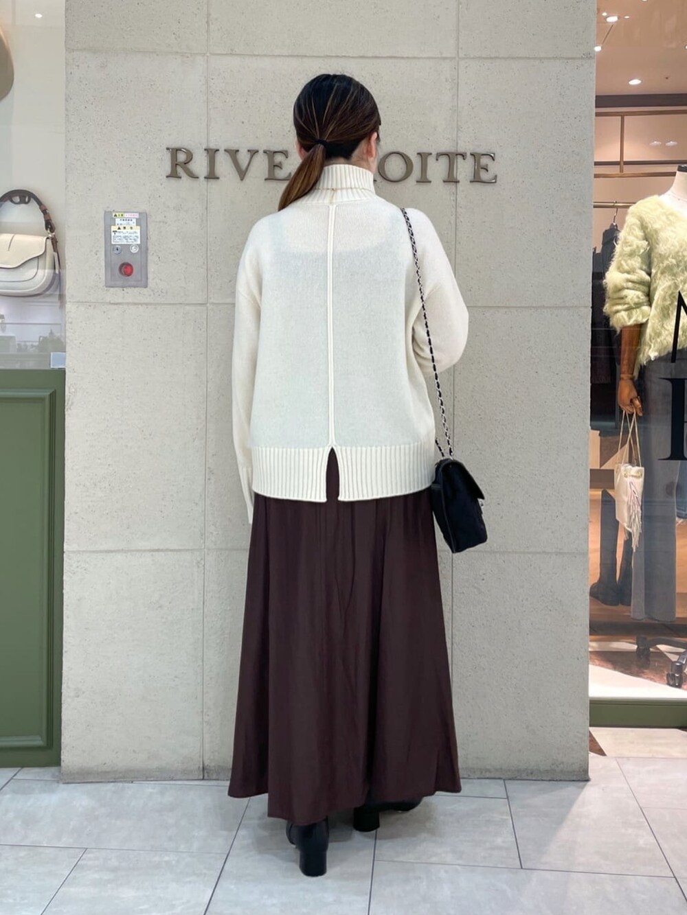 イエロー系のボストンバッグ、ホワイト系のニット/セーター、グレー系のその他アウターを着用したレディースの秋コーディネートの4枚目の写真