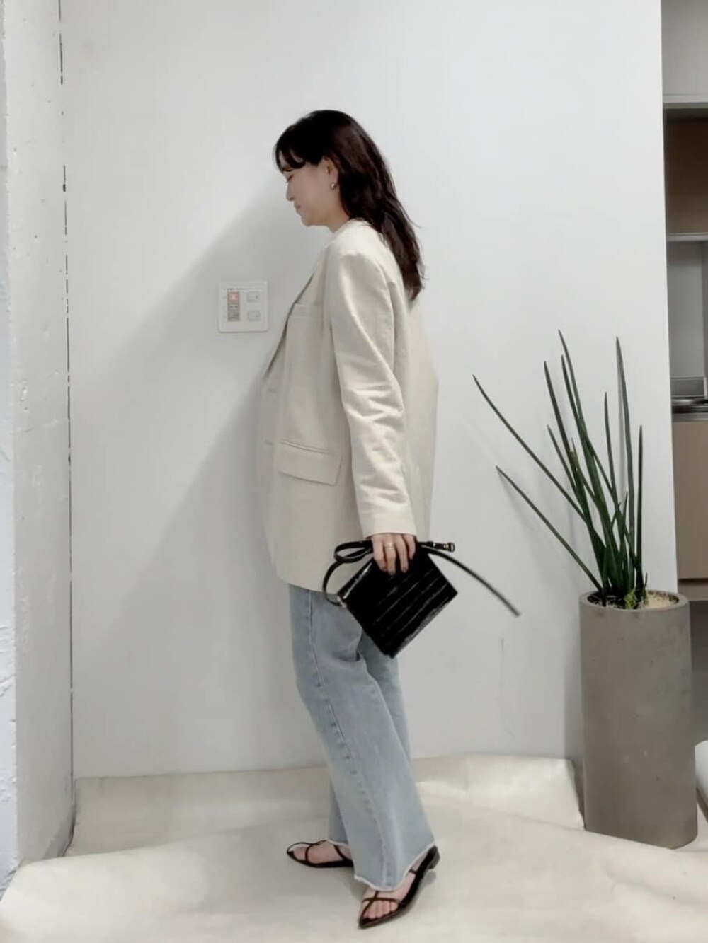 ベージュ系のテーラードジャケット、ホワイト系のニット/セーター、ブルー系のデニムパンツを着用したレディースの冬コーディネートの2枚目の写真