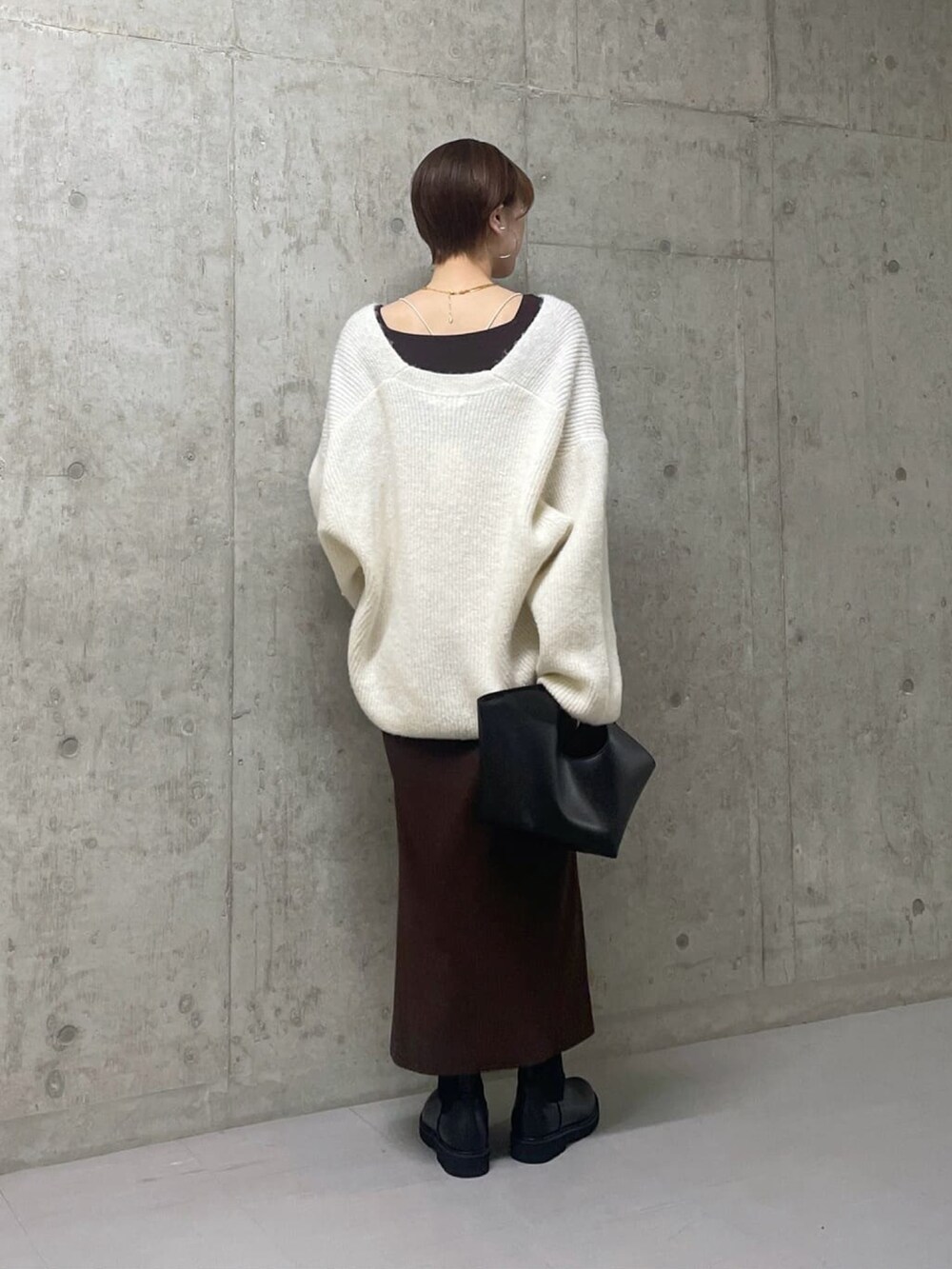 ホワイト系のニット/セーター、ブラウン系のワンピース/ドレス、ブラック系のハンドバッグを着用したレディースの冬コーディネートの2枚目の写真