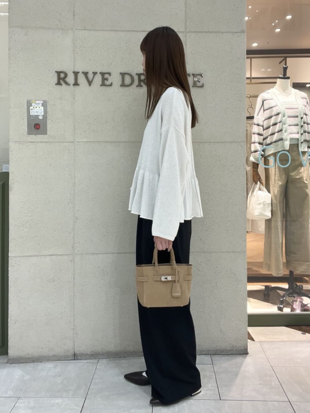 ベージュ系のトートバッグ、ブラウン系のその他シューズ、ホワイト系のニット/セーターを着用したレディースの春コーディネートの2枚目の写真