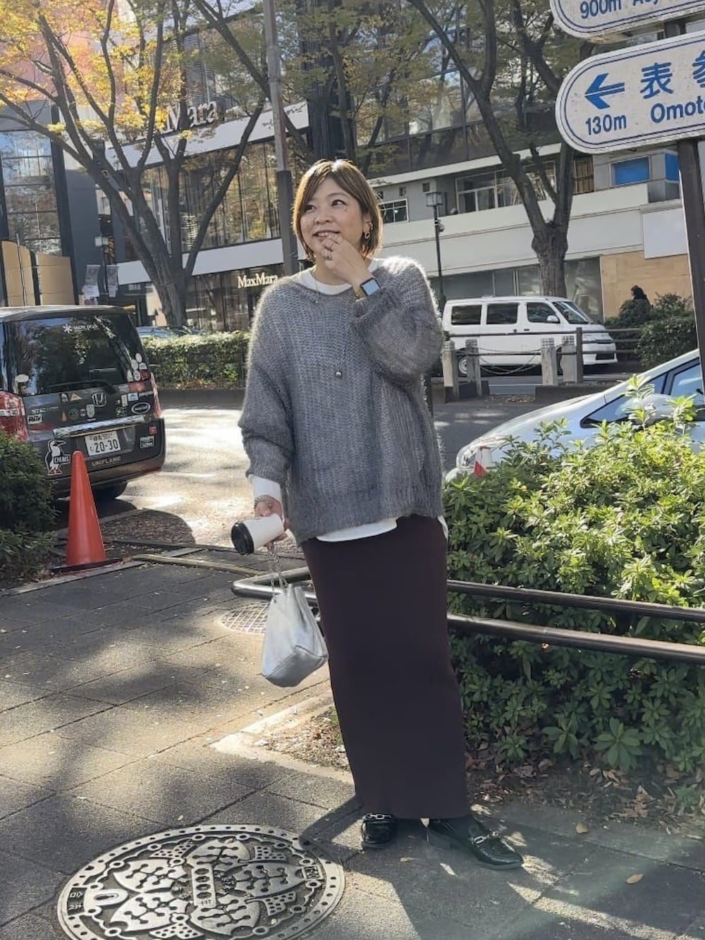 グレー系のニット/セーター、ホワイト系のシャツ/ブラウス、シルバー系のショルダーバッグを着用したレディースの冬コーディネートの2枚目の写真