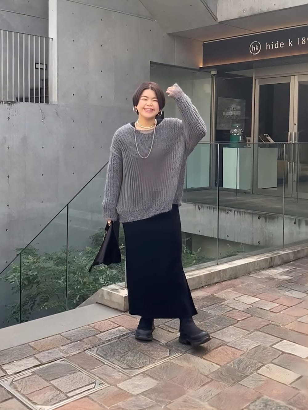 グレー系のニット/セーター、グレー系のワンピース、ブラック系のブーツを着用したレディースの冬コーディネートの2枚目の写真