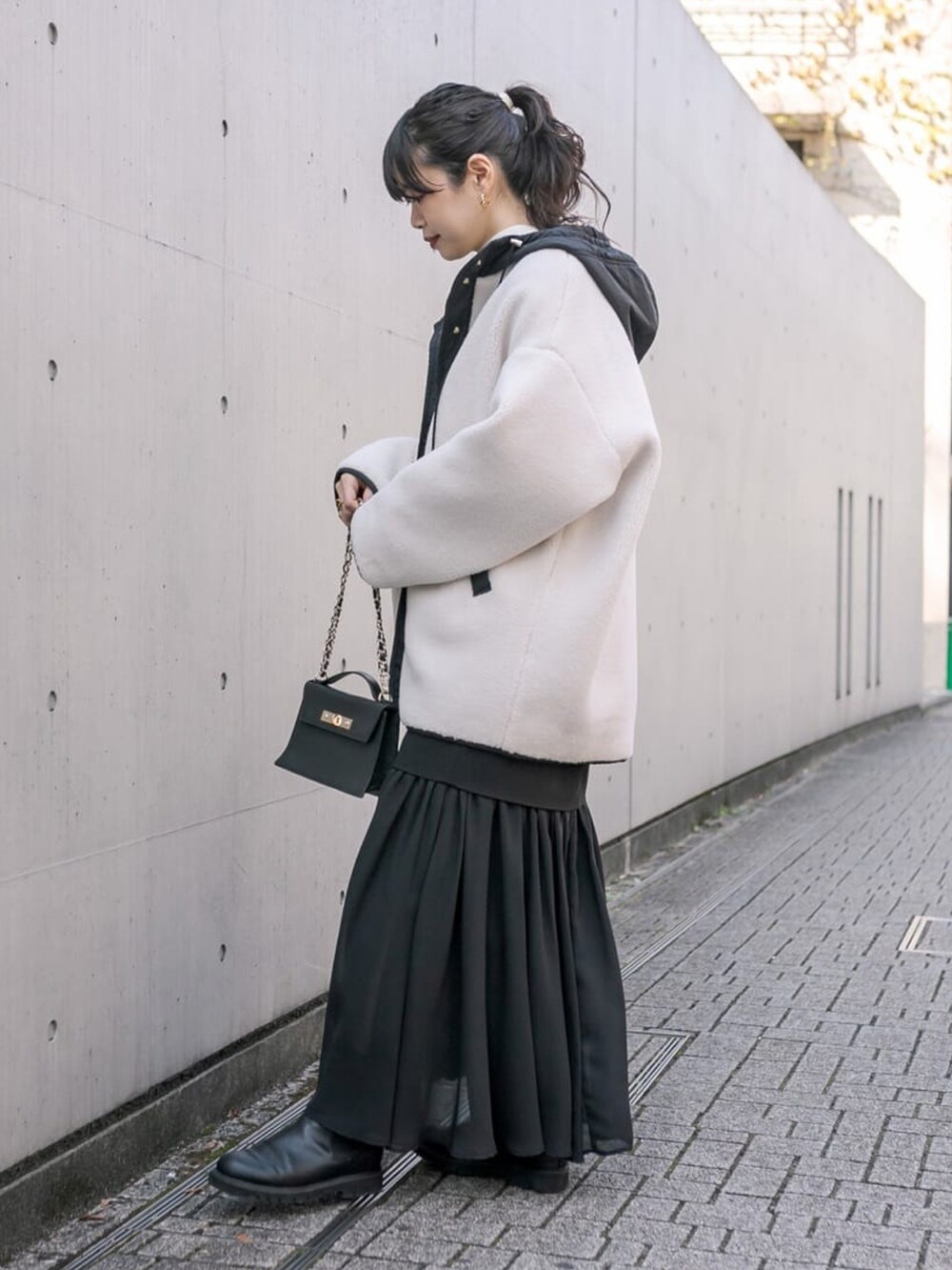 ブラック系のスカート、レッド系のニット/セーター、ブラック系のブーツを着用したレディースの冬コーディネートの2枚目の写真