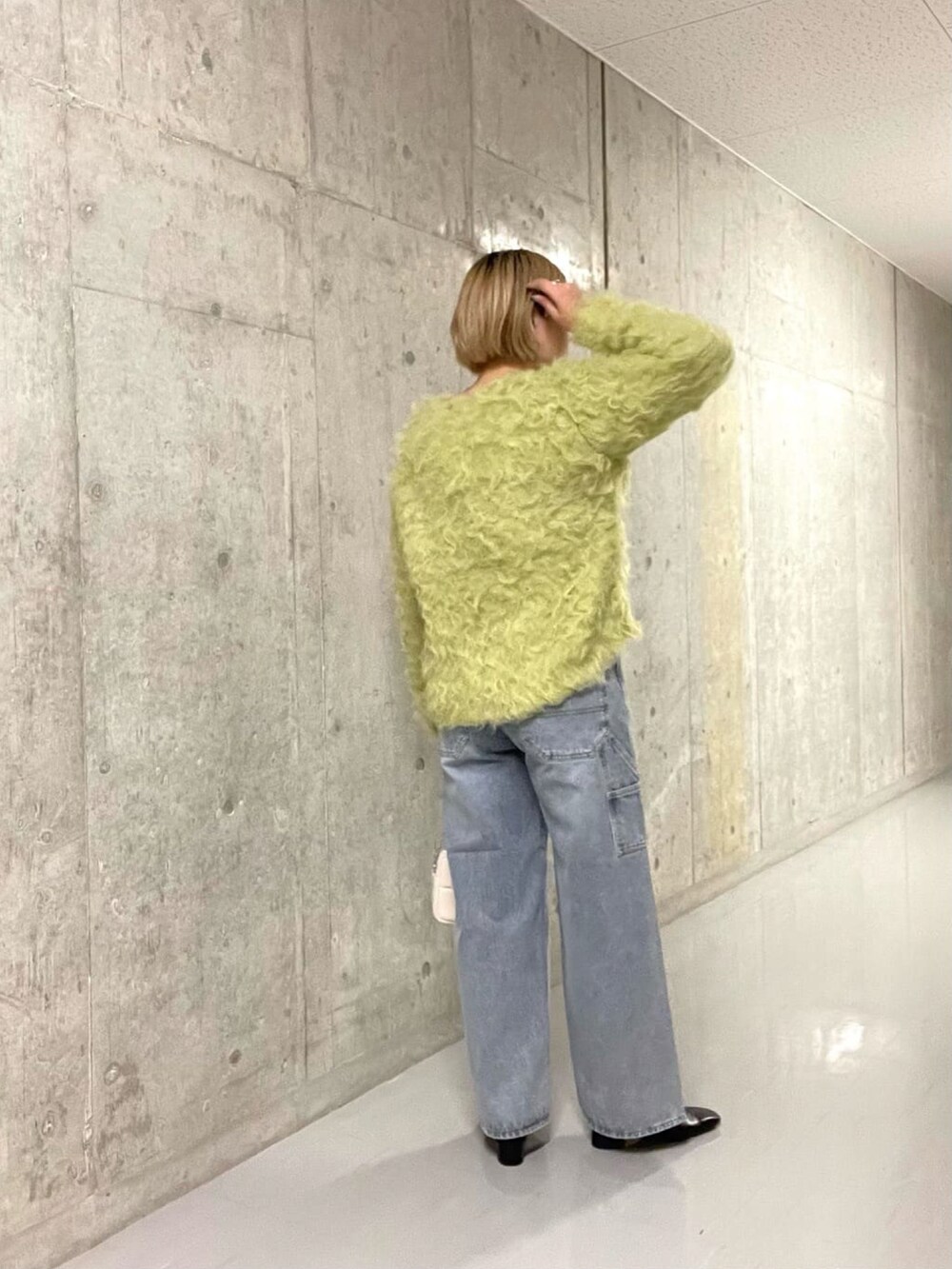 グリーン系のニット/セーター、ブルー系のデニムパンツを着用したレディースの冬コーディネートの4枚目の写真