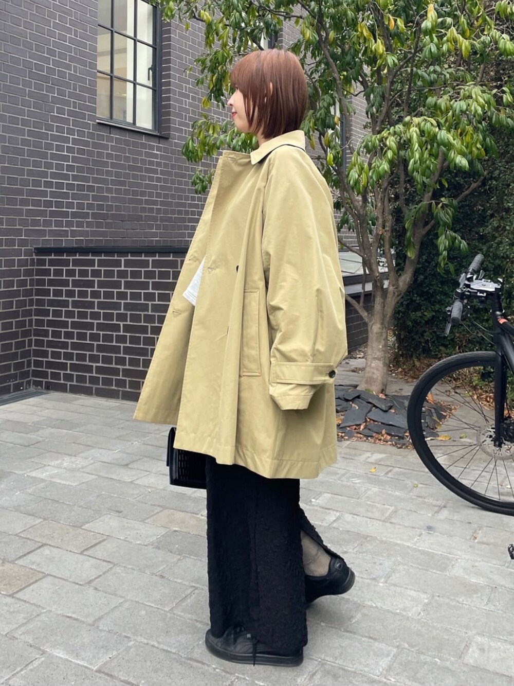 ベージュ系のトレンチコート、グレー系のスウェット、ブラック系のスカートを着用したレディースの冬コーディネートの3枚目の写真