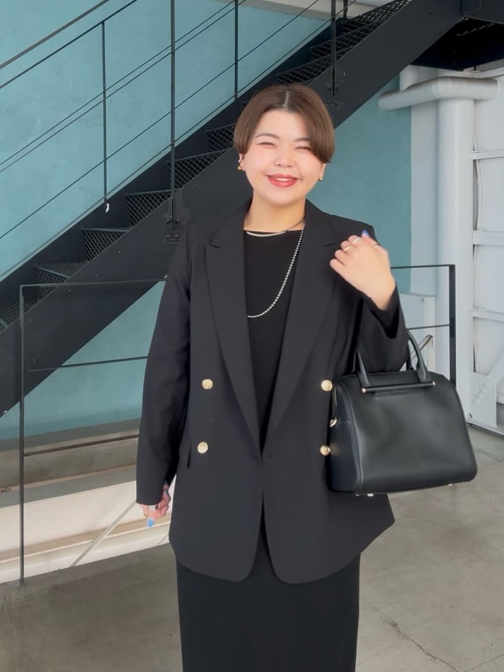 ブラック系のテーラードジャケット、ブラック系のボストンバッグ、ブラック系のワンピースを着用したレディースの冬コーディネートの4枚目の写真