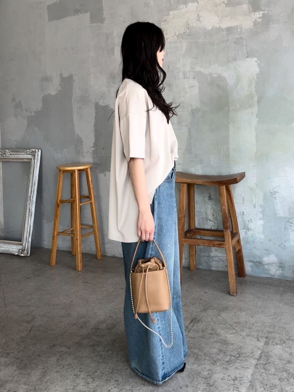 ベージュ系のTシャツ/カットソー、ブルー系のデニムパンツ、イエロー系のハンドバッグを着用したレディースの夏コーディネートの2枚目の写真