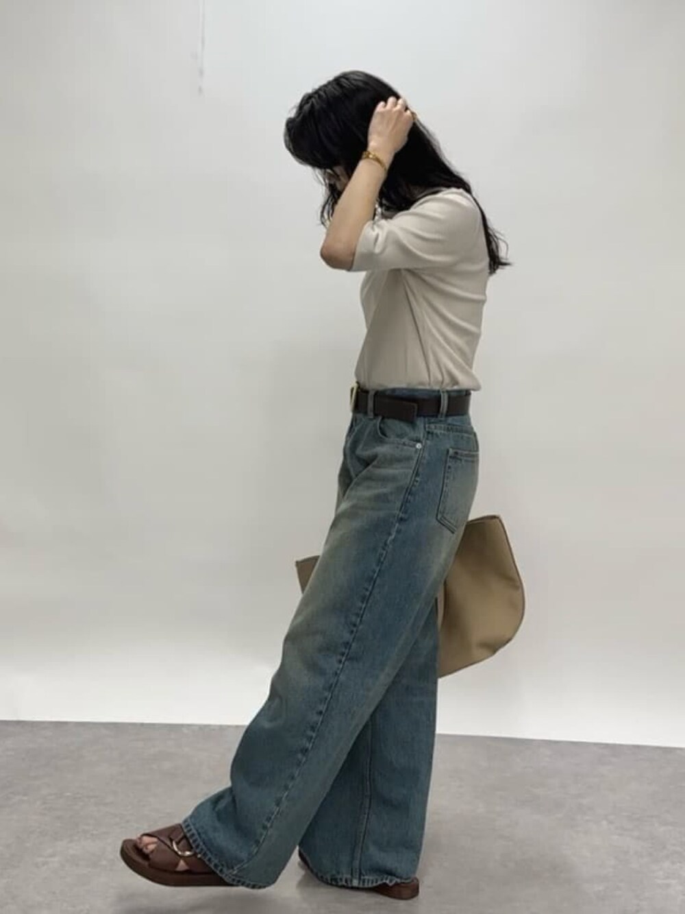 グレー系のTシャツ/カットソー、ブルー系のデニムパンツ、ベージュ系のトートバッグを着用したレディースの春コーディネートの2枚目の写真