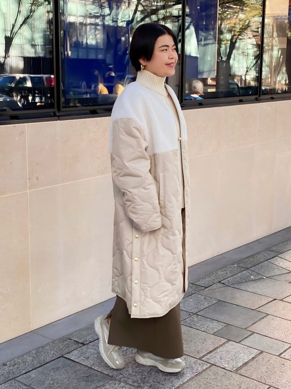 ベージュ系のダウンジャケット/コート、ホワイト系のニット/セーター、グリーン系のスカートを着用したレディースの秋コーディネートの2枚目の写真