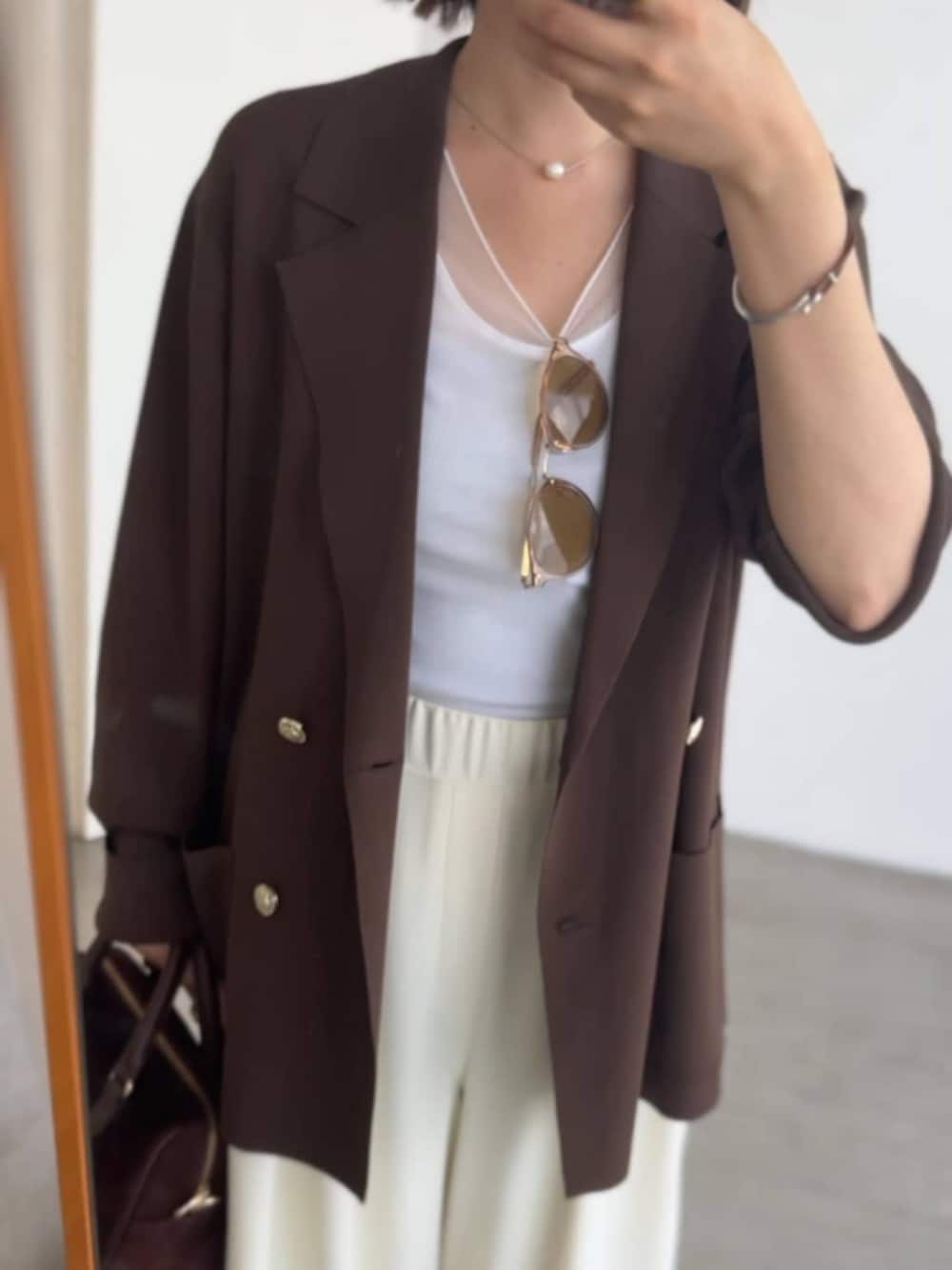 ホワイト系のスラックス、グレー系のパンプス、ホワイト系のキャミソールを着用したレディースの夏コーディネートの4枚目の写真