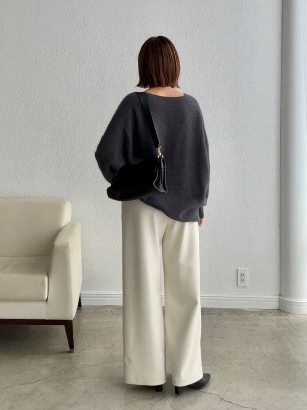 グレー系のニット/セーター、ブラック系のショルダーバッグ、ホワイト系のその他パンツを着用したレディースの秋コーディネートの3枚目の写真