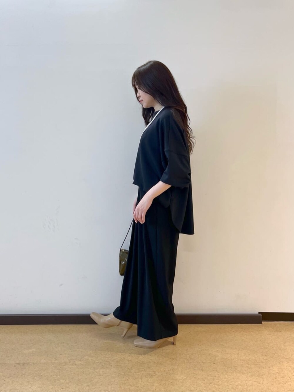 ブラック系のスラックス、ブラック系のTシャツ/カットソー、グリーン系のショルダーバッグを着用したレディースの春コーディネートの2枚目の写真