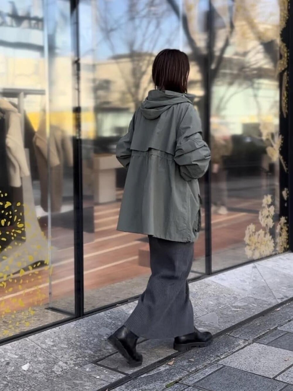 グレー系のワンピース、グリーン系のマウンテンパーカー、ブラック系のブーツを着用したレディースの冬コーディネートの2枚目の写真