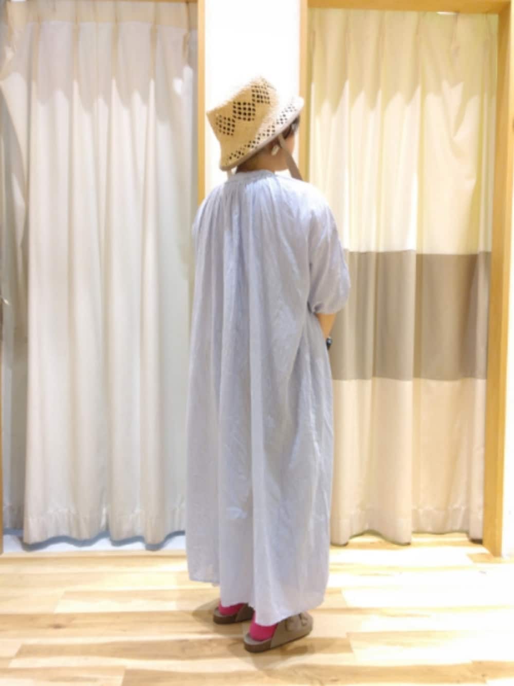 ブルー系のワンピース、ベージュ系のハンドバッグ、ブラウン系のサンダルを着用したレディースの夏コーディネートの2枚目の写真