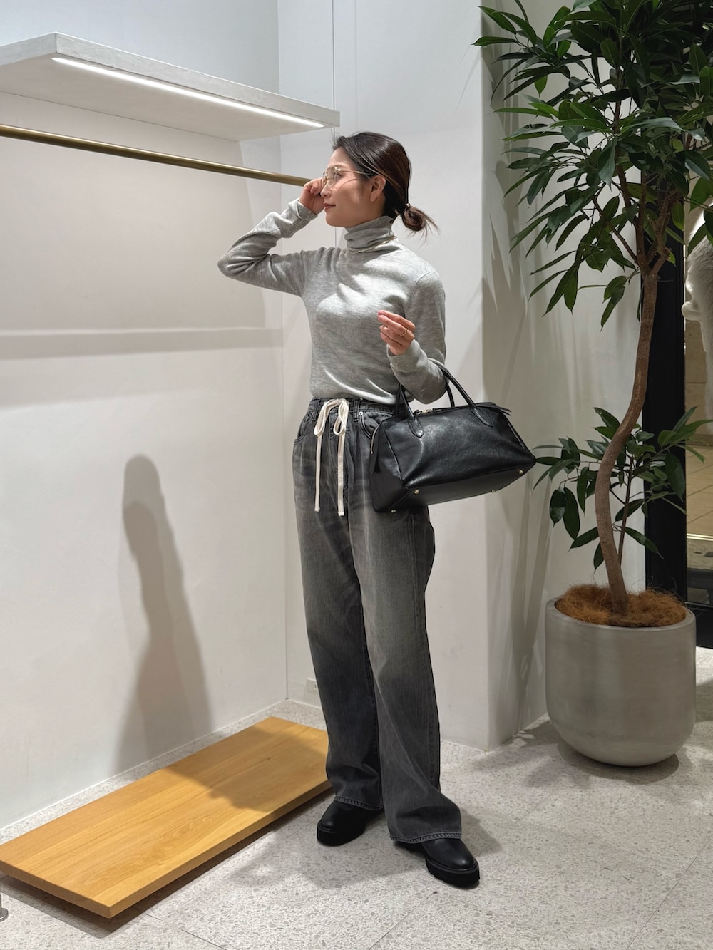 ブラック系のブーツ、グレー系のデニムパンツ、ブラック系のトートバッグを着用したレディースの秋コーディネートの4枚目の写真