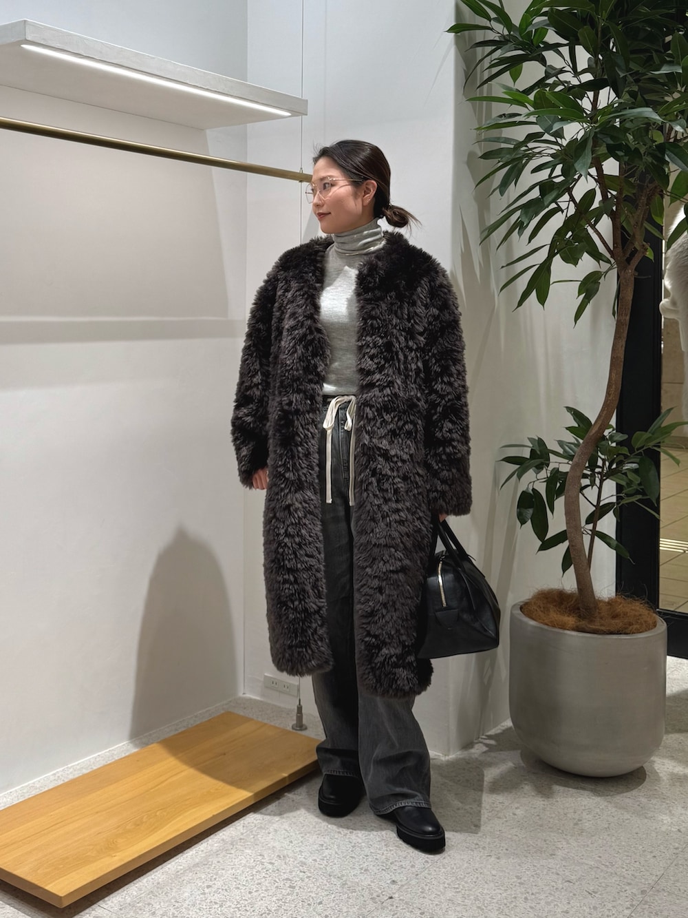 ブラック系のブーツ、グレー系のデニムパンツ、ブラック系のトートバッグを着用したレディースの秋コーディネートの2枚目の写真