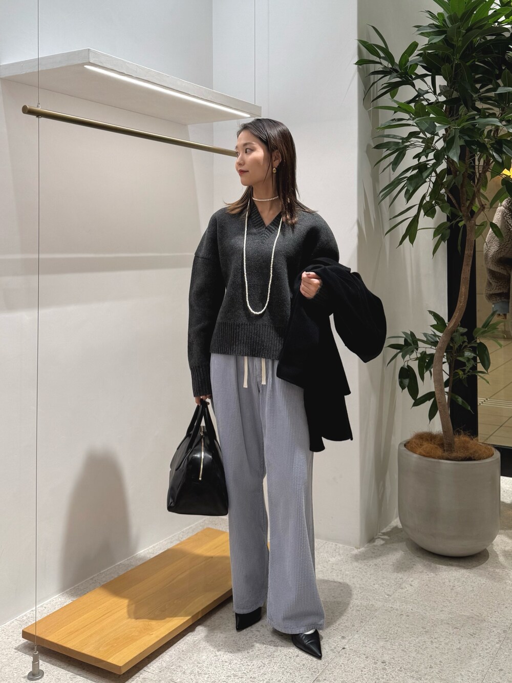 ブラック系のパンプス、ブラック系のトートバッグ、ブルー系のその他パンツを着用したレディースの秋コーディネートの3枚目の写真