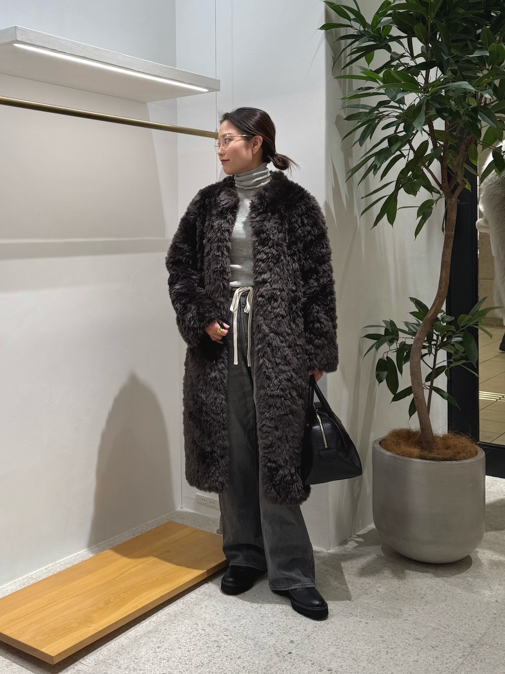 ブラック系のブーツ、グレー系のデニムパンツ、ブラック系のトートバッグを着用したレディースの秋コーディネートの6枚目の写真