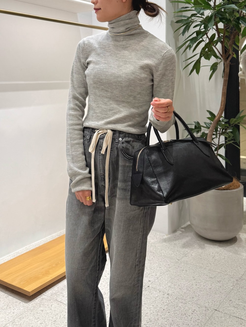 ブラック系のブーツ、グレー系のデニムパンツ、ブラック系のトートバッグを着用したレディースの秋コーディネートの5枚目の写真