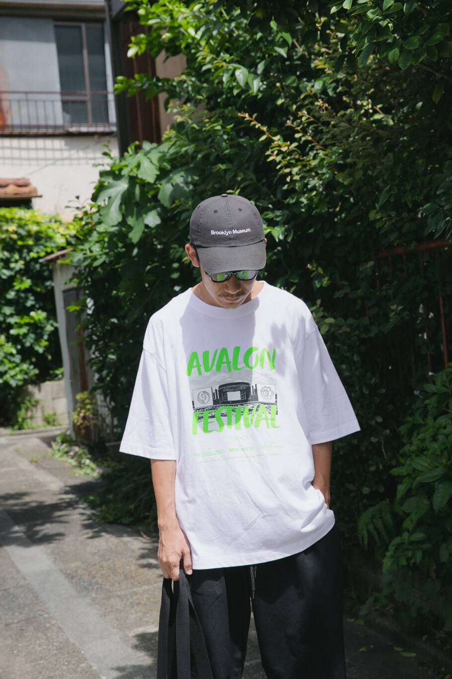 ブルー系のその他パンツ、ブラック系のトートバッグ、ホワイト系のTシャツ/カットソーを着用したメンズの夏コーディネートの3枚目の写真