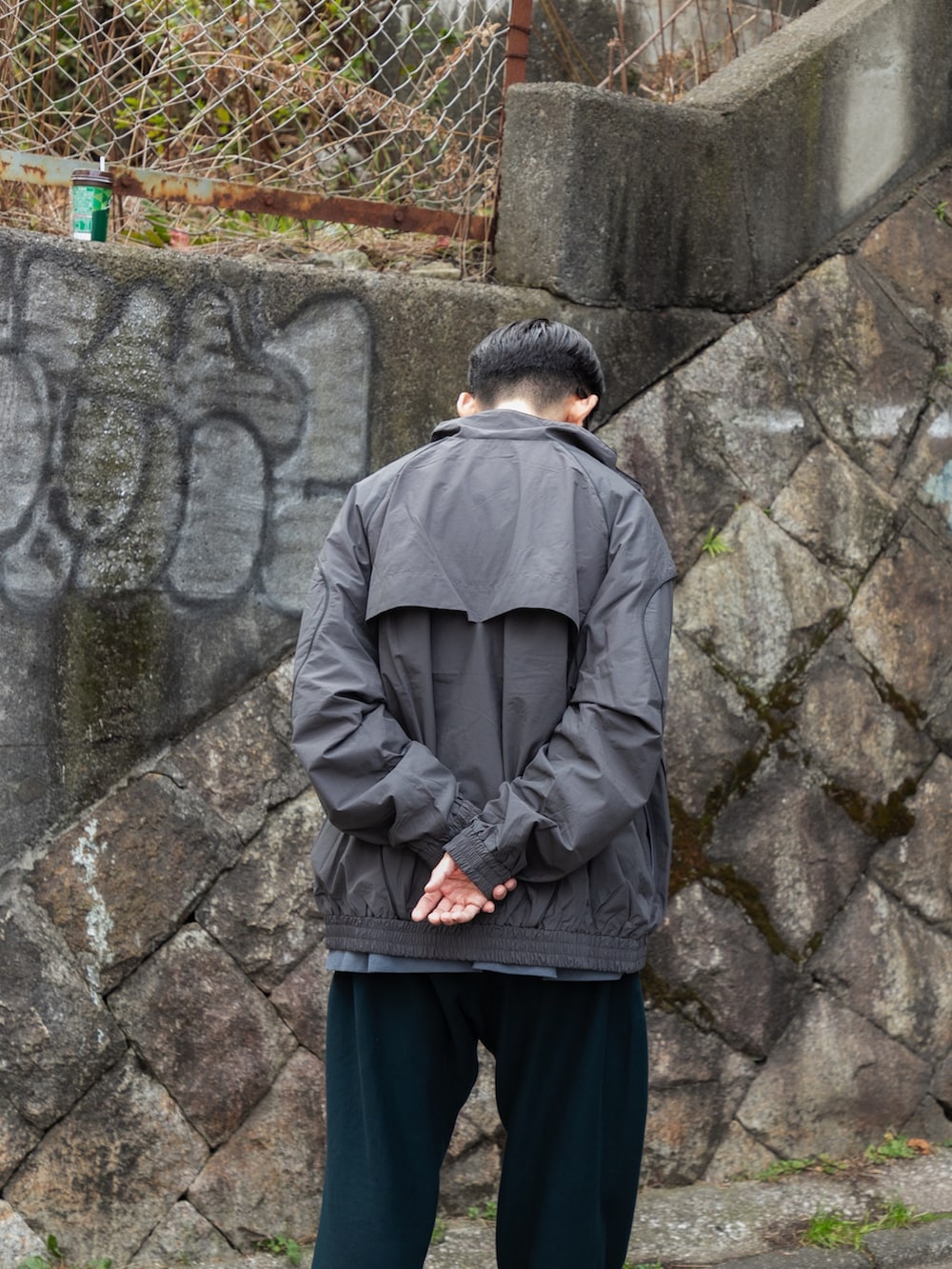 グレー系のブルゾン、ブルー系のその他パンツ、ブラック系のスニーカーを着用したメンズの冬コーディネートの4枚目の写真