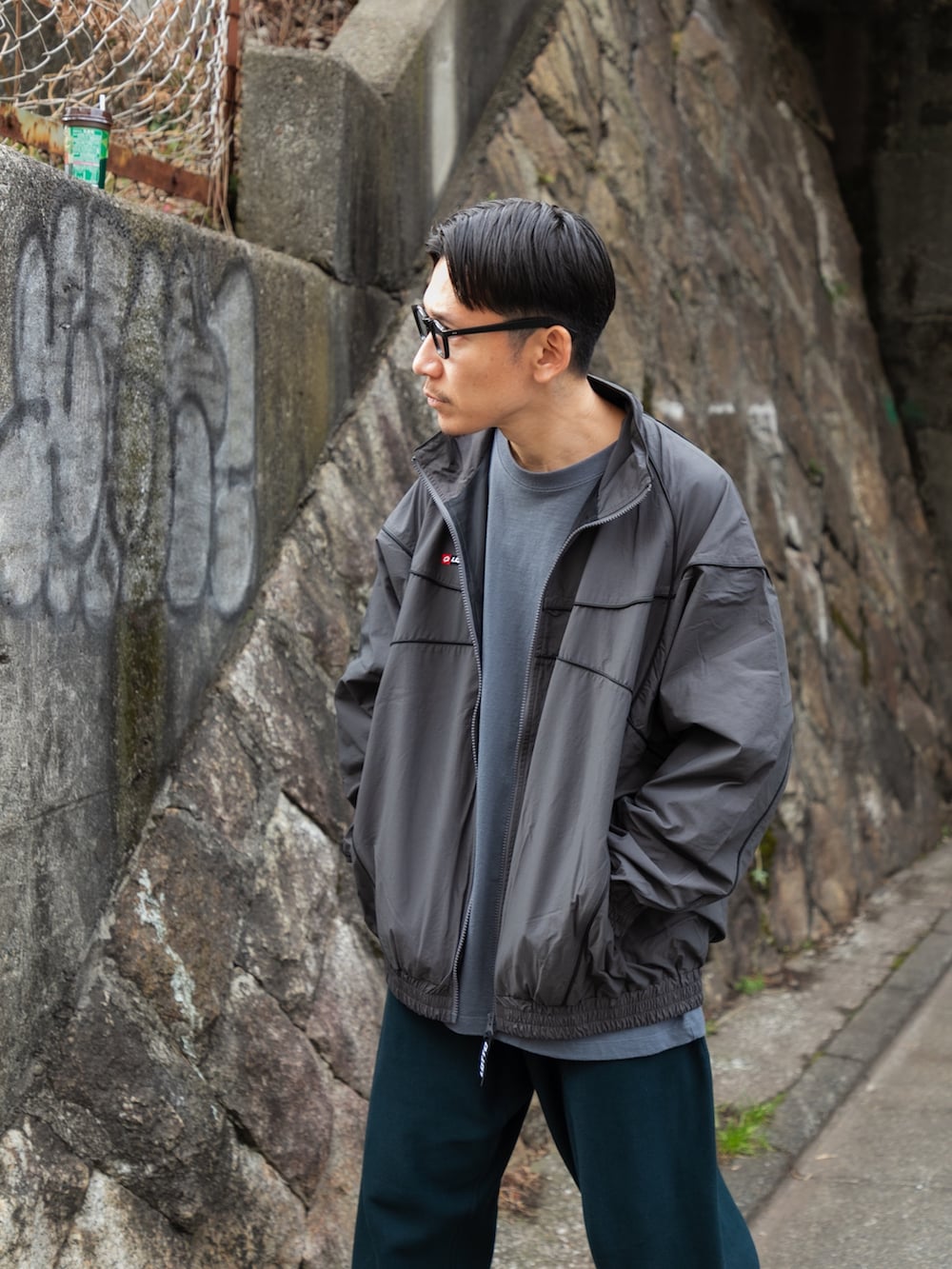 グレー系のブルゾン、ブルー系のその他パンツ、ブラック系のスニーカーを着用したメンズの冬コーディネートの6枚目の写真