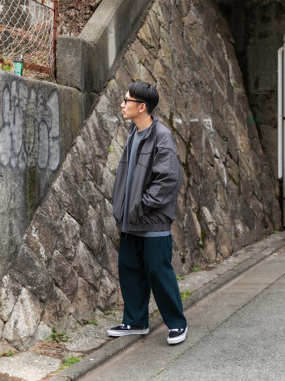 グレー系のブルゾン、ブルー系のその他パンツ、ブラック系のスニーカーを着用したメンズの冬コーディネートの2枚目の写真