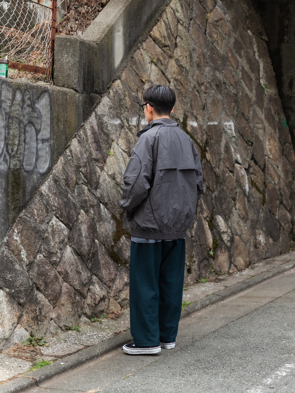 グレー系のブルゾン、ブルー系のその他パンツ、ブラック系のスニーカーを着用したメンズの冬コーディネートの3枚目の写真