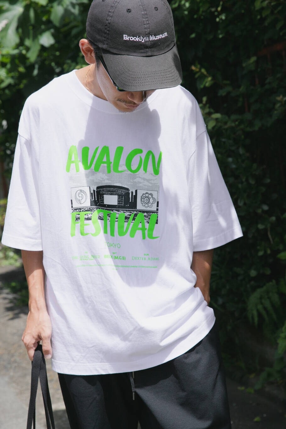 ブルー系のその他パンツ、ブラック系のトートバッグ、ホワイト系のTシャツ/カットソーを着用したメンズの夏コーディネートの4枚目の写真