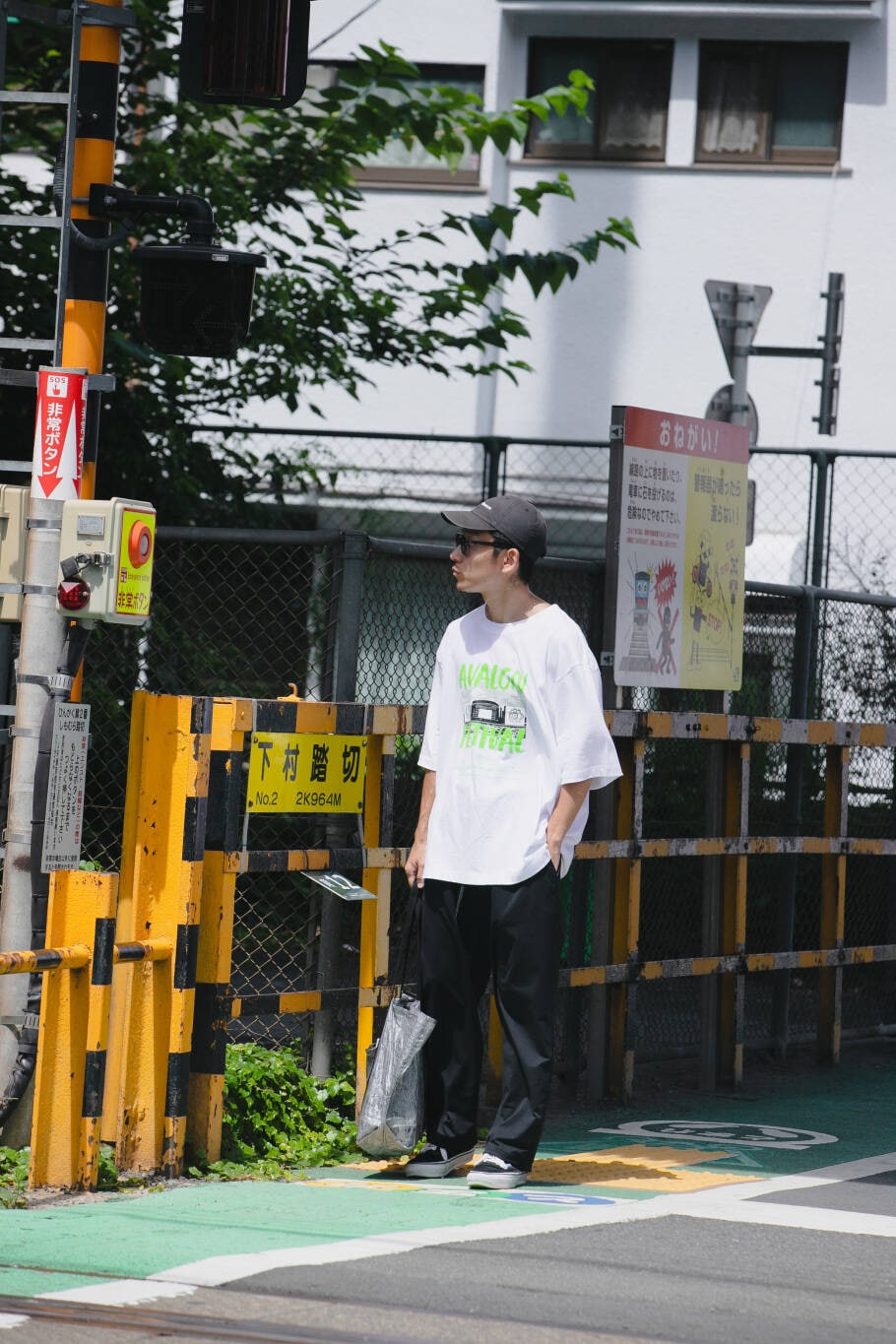 ブルー系のその他パンツ、ブラック系のトートバッグ、ホワイト系のTシャツ/カットソーを着用したメンズの夏コーディネートの2枚目の写真