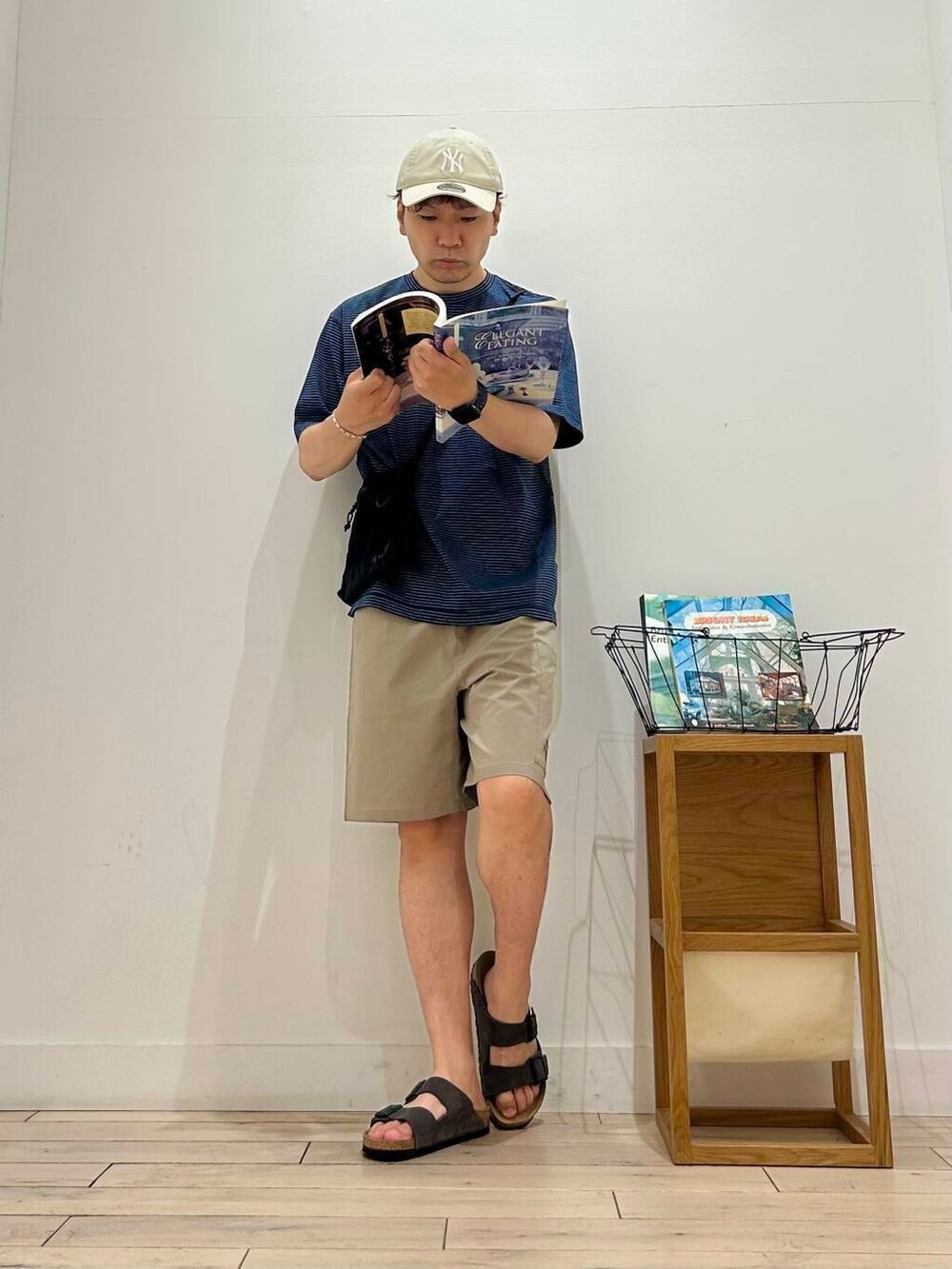 ブラック系のショルダーバッグ、ベージュ系のその他パンツ、ブルー系のTシャツ/カットソーを着用したメンズの夏コーディネートの2枚目の写真