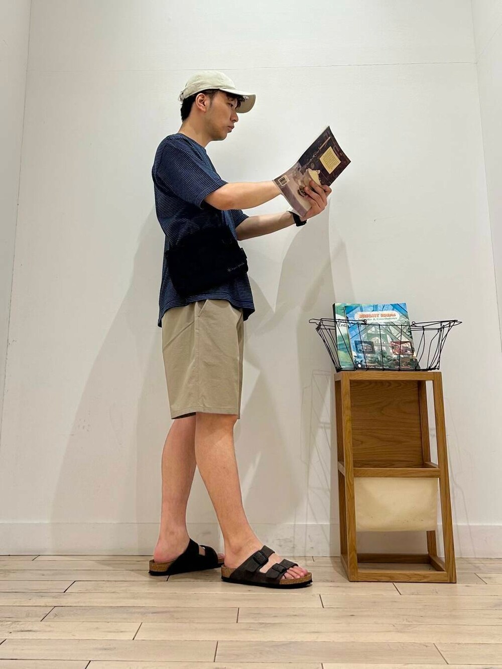 ブラック系のショルダーバッグ、ベージュ系のその他パンツ、ブルー系のTシャツ/カットソーを着用したメンズの夏コーディネートの6枚目の写真