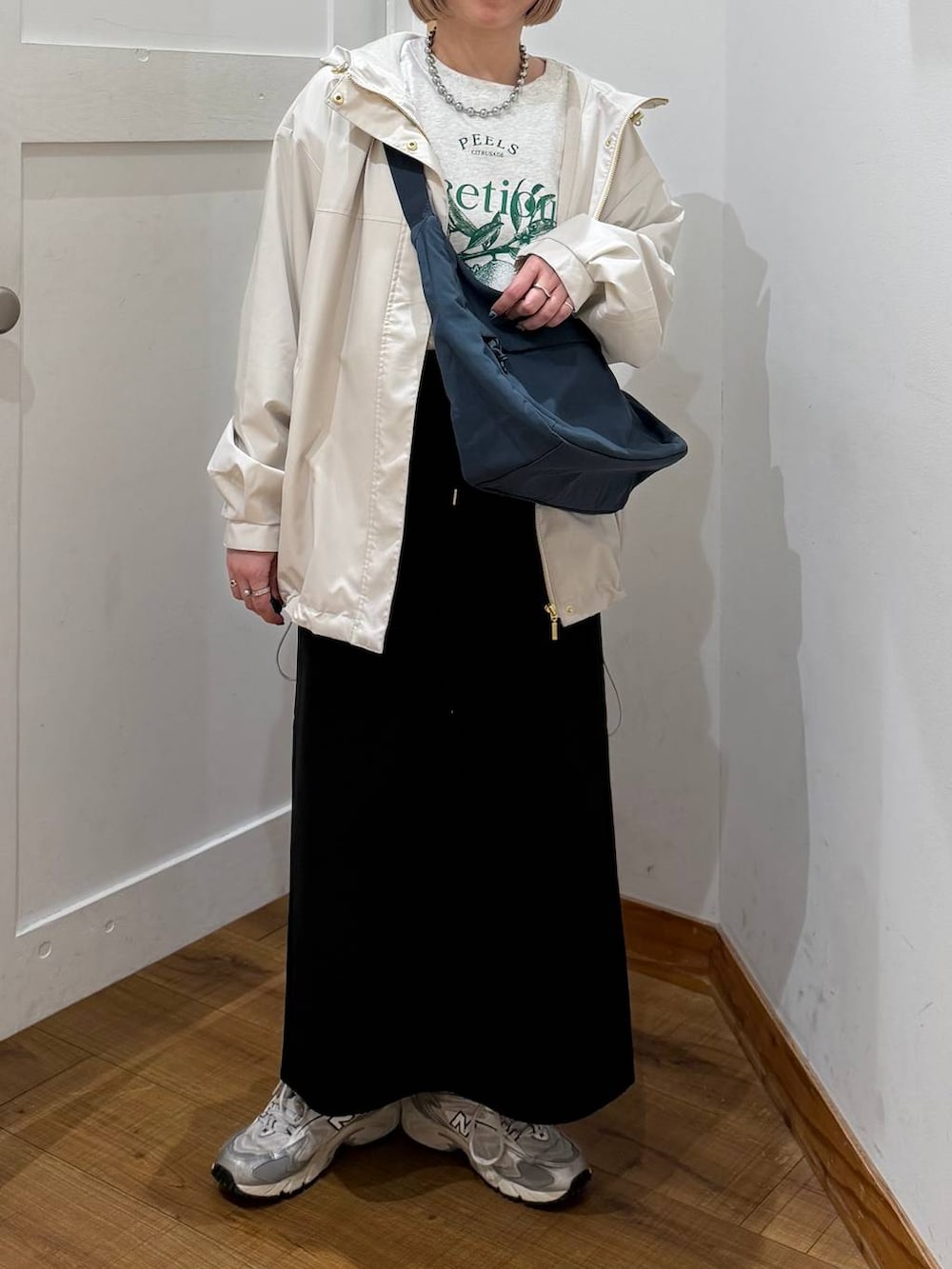 グレー系のスウェット、ベージュ系のマウンテンパーカー、グリーン系のショルダーバッグを着用したレディースの冬コーディネートの2枚目の写真